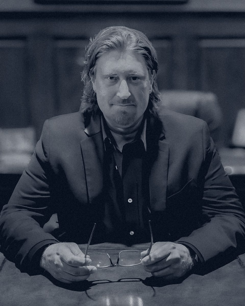 Paul Mattson, founder of Unwrapped, seated at his desk with his glasses in his hands